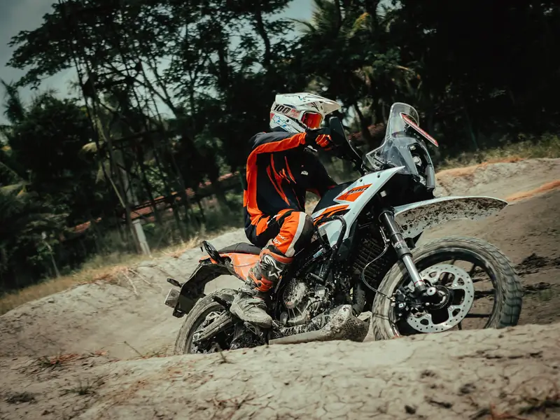Rider standing on the pegs of an adventure bike in a sandy corner