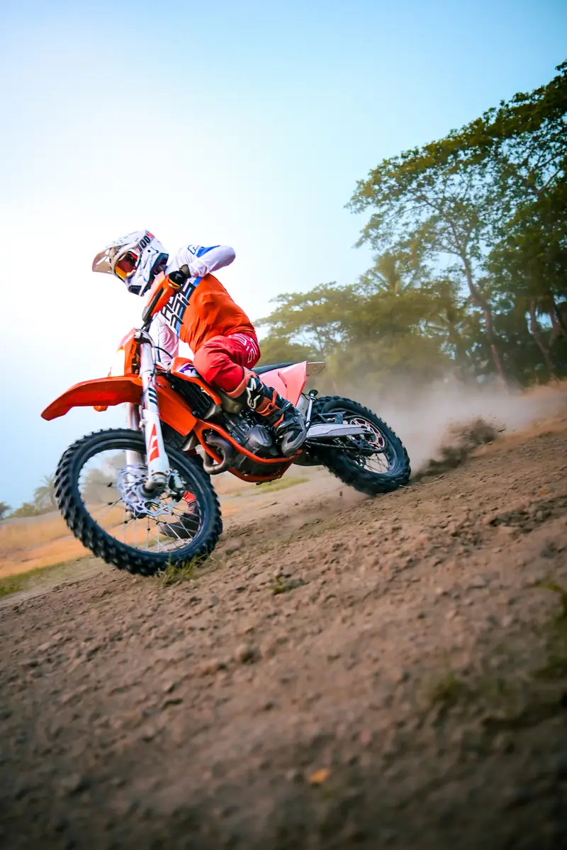 Low-angle shot of a dirt bike leaning hard through a dusty corner