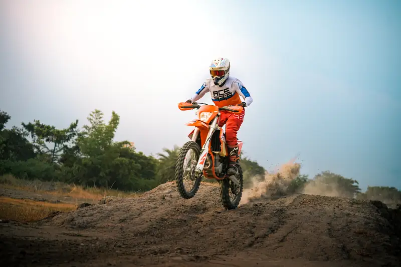 Dirt bike landing off a mound with dust trailing behind