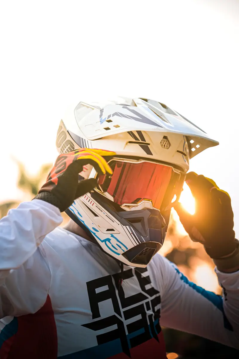 Rider adjusting goggles with the sun flaring behind the helmet