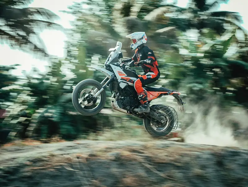 Panning shot of an adventure bike in the air with blurred palm trees