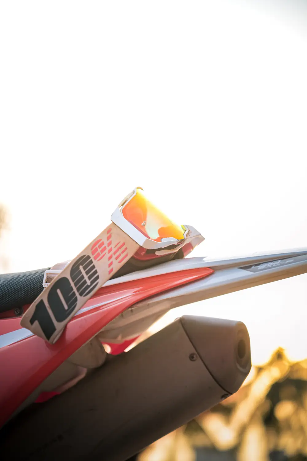 Racing goggles resting on the rear fender of a dirt bike